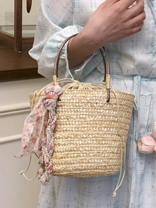 Woven straw bucket bag with drawstring closure and floral scarf for summer beach vacation
