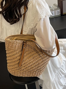 Women's woven straw tote bag with brown leather straps for summer beach or commute