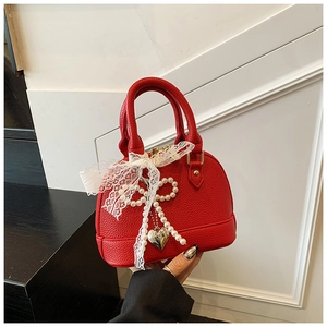 Detail of red lychee grain leather shell bag with pearl bow and lace ribbon accent
