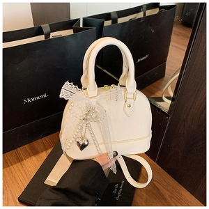 Detailed macro view of white lychee textured shell bag with lace bow and pearl charms