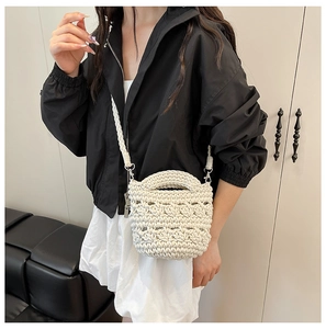 Détail d'un sac seau tissé à la main crème avec texture et anneaux en métal argenté