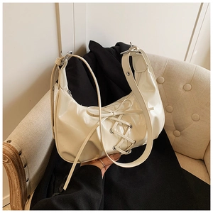 Detailansicht der cremefarbenen Hobo-Tasche mit Schnürung und glänzendem Leder