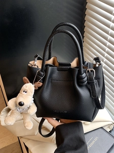 Chic black lychee grain leather bucket bag with top handles and a cute puppy charm