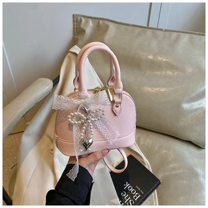 Detail of pink shell bag with white lace bow and pearl heart pendant charm