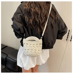 Détail du sac seau tissé à la main en blanc cassé avec connecteurs de bandoulière en métal