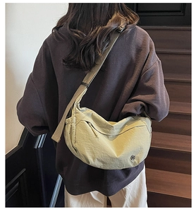 Detailed back view of model wearing a light olive green nylon dumpling crossbody bag