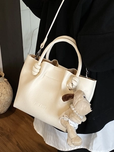 Chic white lychee grain leather bucket bag with cute plush puppy charm and shoulder strap