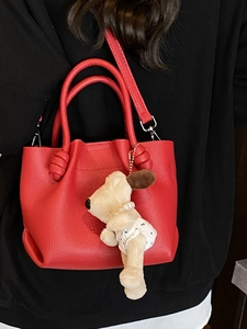 Red lychee texture bucket bag with knotted handles and a cute cartoon puppy pendant