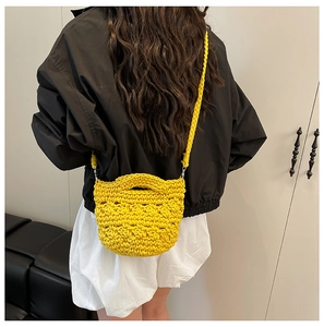 Gros plan sur un sac seau jaune crocheté à la main avec motif ajouré et longue bandoulière
