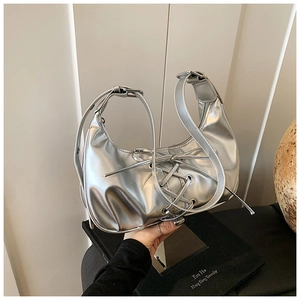 Detail der silbernen Halbmond-Tasche mit Schnürung, Metallösen und Metallic-Finish