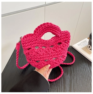 Détail d'un sac seau tissé main rose fuchsia avec bandoulière tricotée et fermoir métal