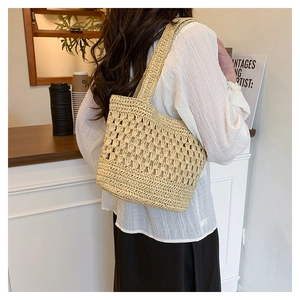 Détail du sac cabas en paille tissé à la main montrant la texture et les bretelles