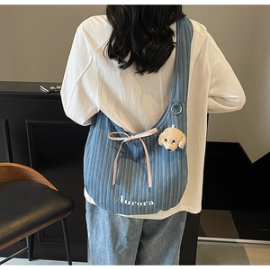 Detail of blue striped denim shoulder bag with Aurora text and cute puppy pendant