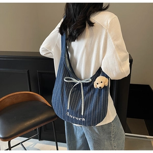 Detail of blue striped denim tote with bow, teddy charm and Aurora embroidery