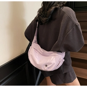 Detail of light purple crescent crossbody bag with adjustable strap and metal logo