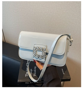Close-up of shiny light blue patent leather bag with a large crystal buckle detail