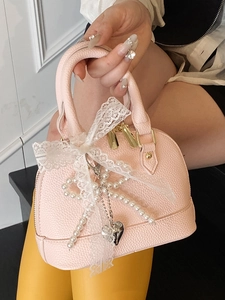 Pink shell handbag in lychee leather with white lace bow and pearl chain detail