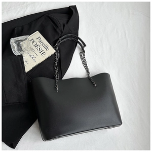 Close-up of a minimalist black tote bag with metal chain strap on aesthetic background