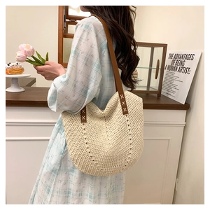 Detail of hand-woven beige tote with brown leather strap and decorative stitching