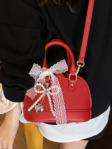 Red shell cross-body bag with lace bow, pearl heart pendant, and lychee grain leather