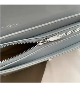 Close-up detail of smooth silver metal zipper on light blue patent leather bag