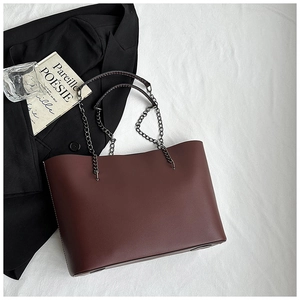 Close-up of burgundy leather tote bag with chain strap on minimalist office backdrop