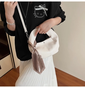 Détail du sac croissant blanc avec foulard en soie géométrique marron sur la poignée