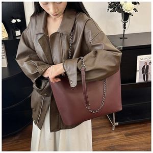 Burgundy oversized tote bag with chain strap styled with brown leather coat and white dress