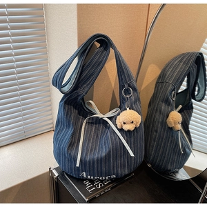 Detail view of denim tote bag with white ribbon bow and cute teddy dog plush charm