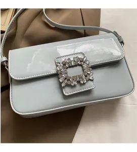 Detail of light blue patent leather crossbody bag featuring a large square crystal buckle