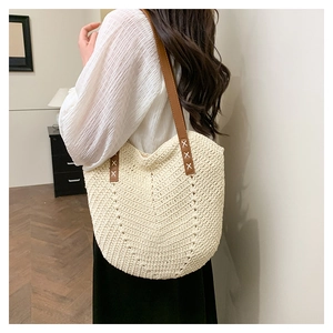 Detailed close-up of woven tote bag with white X-shaped stitching on leather straps