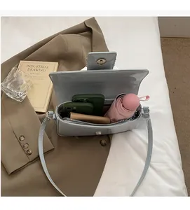 Spacious light blue patent leather bag interior holding phones, wallet and umbrella
