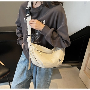 Detail of beige nylon crossbody bag featuring adjustable wide strap and plastic buckle