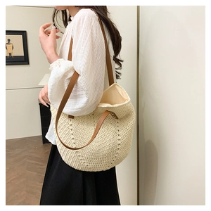 Detail shot of the beige straw tote bag showing woven texture and brown leather straps