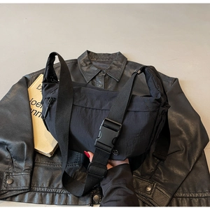 Detail of adjustable nylon strap and large plastic buckle on a casual black crossbody bag