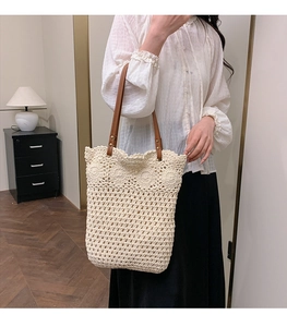 Détail du cabas en paille tissé blanc cassé avec motifs floraux et anses en cuir marron