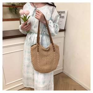 Close-up of woven straw tote bag featuring V-shaped texture and brown leather handles