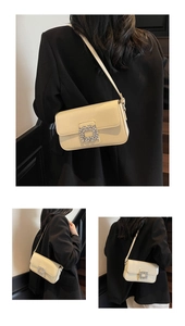 Detail of cream patent leather shoulder bag featuring a sparkling rhinestone square buckle