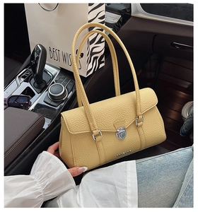Detail of yellow pebbled leather handbag with silver twist lock on a luxury car console
