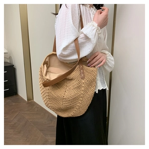 Close-up of the woven straw tote bag texture with brown leather handle and stitching