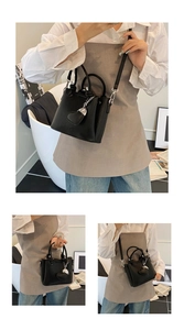 Détail du sac seau noir en cuir grainé avec poignées anneaux et pendentif cœur élégant