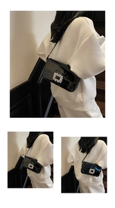 Detail showing high-gloss black patent leather shoulder bag with a square rhinestone buckle