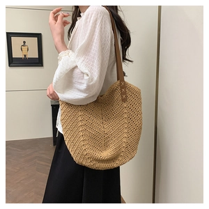 Detail showing handwoven straw shoulder bag with durable brown leather straps and cross stitching