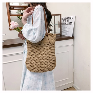 Détail du sac cabas en paille tissé avec anses en cuir marron et rivets de renfort