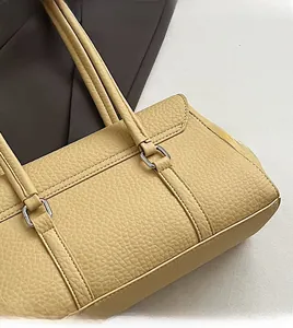 Close-up of beige lychee texture leather bag with silver hardware and shoulder strap