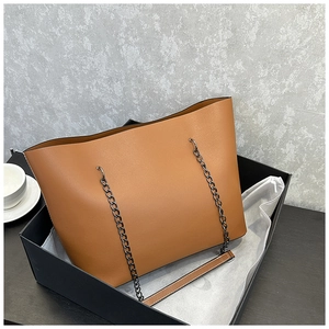 Close-up of textured leather tote bag with black metal chain straps in elegant gift box