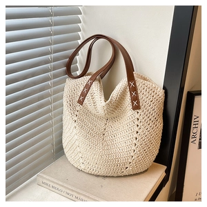 Close-up of beige straw tote bag with V-shaped weave and brown leather shoulder straps
