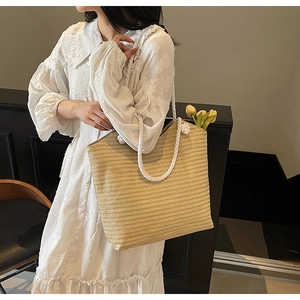 Close-up of woven straw tote bag with thick cotton rope handles and yellow tulip detail