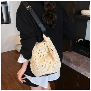 Detail showing the adjustable black leather strap and woven texture of the bucket bag