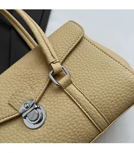 Close-up of beige lychee grain leather handbag featuring silver metal twist lock and stitching